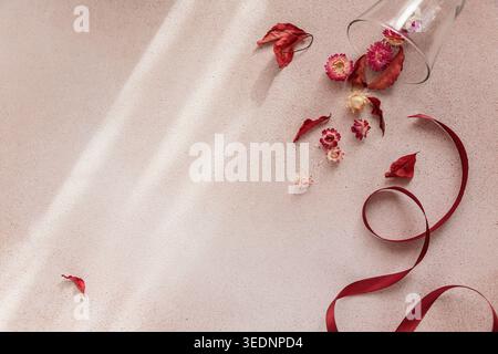 Autumn composition from ribbon and wineglass full of red dried flowers and leaves Stock Photo