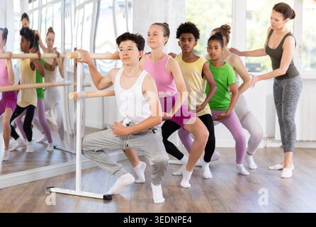 Teenager practicing grand plie at barre at group ballet class Stock Photo