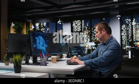 Tech startup IT expert developing artificial intelligence algorithms in high rise office late at night. System administrator debugging neural network brain models on screens Stock Photo
