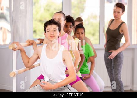 Teenager practicing grand plie at barre at group ballet class Stock Photo