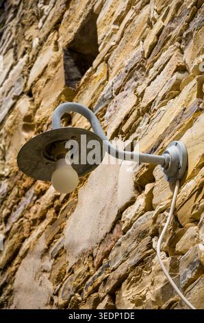 Rustic Wall Lamp on Weathered Stone Exterior Stock Photo