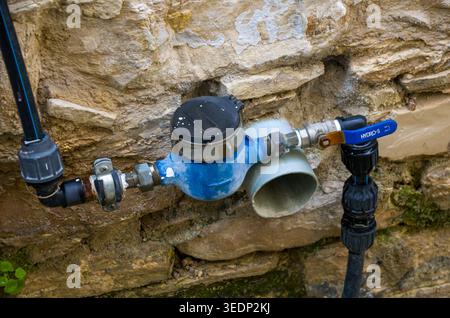 Outdoor Water Meter and Shutoff Valve Mounted on Stone Wall Stock Photo