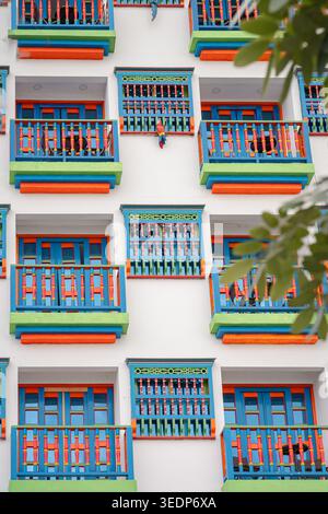 Vibrant balconies and windows with ornate blue, orange, and green details creating an eye-catching pattern on a traditional white architectural exteri Stock Photo