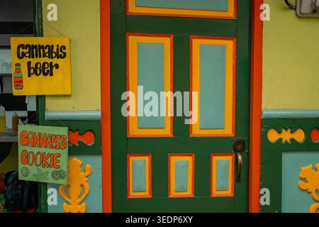 Vibrant green door with orange and yellow details features handmade signs advertising cannabis-infused beer and cookies, highlighting legal cannabis p Stock Photo