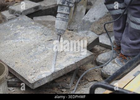 Construction worker uses jackhammer on pavement in a city Stock Photo