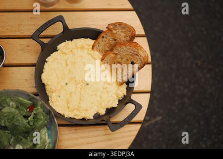 Scrambled eggs with toast served on a wooden table Stock Photo