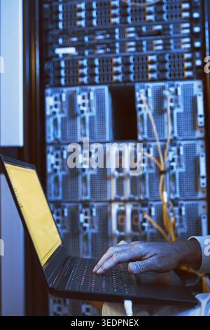 Typing, laptop and hands of person in server room for diagnostics, cybersecurity and network. Database, engineer and worker on computer for software Stock Photo