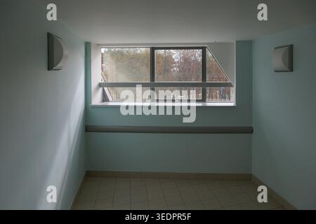 Window lets in natural light, casting gentle shadows. Two wall-mounted sconces provide subtle illumination Stock Photo