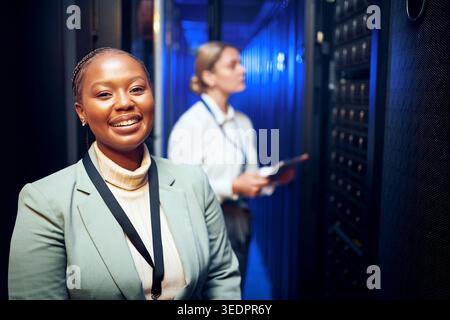 Portrait, woman and programmer with smile in server room for about us, inspection and cybersecurity. Happy, female person and technician at data Stock Photo