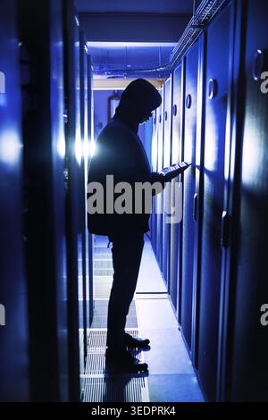 Corrupting even the smallest of weakness in the system. Shot of a hacker using a digital tablet in a server room. Stock Photo