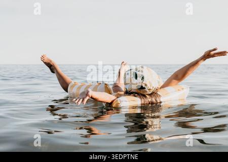 Couple Inflatable Raft Ocean Summer: A couple enjoys a relaxing day floating on an inflatable raft in the ocean during the summer. Stock Photo