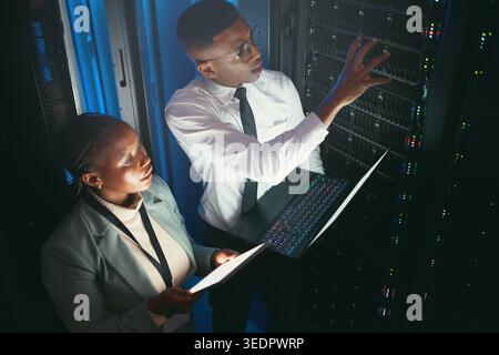 Inspection, review or team in server room with tech, network or system check in datacenter. Engineers, laptop or black people with tablet, fault Stock Photo