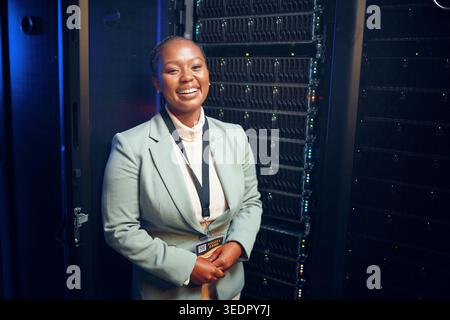 Portrait, black woman and programmer with smile in server room for inspection, cybersecurity and repairs. Happy, technician and data center for backup Stock Photo