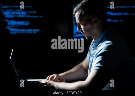 Hacker types code on laptop keyboard. Hacker analyzes system vulnerability at night. Hacker monitors server and database access. Hacker launches cyber Stock Photo