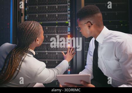 People, tablet and team with cables in server room with cybersecurity, system or inspection for hardware. Programmer, man and woman with app for Stock Photo