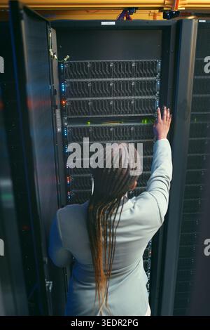 Engineer, woman or inspection in server rack, hardware management or planning for power efficiency. Mainframe upgrade, system check or it specialist Stock Photo