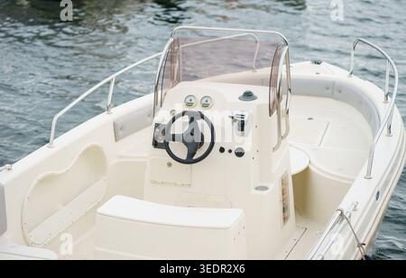 Close view of motorboat cockpit with steering wheel and instruments, leisure boating, navigation concept and calm water background Stock Photo