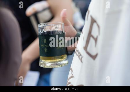Beer Days Festival visitor holds a branded beer glass while standing in the crowd during the outdoor event on Zakyan Street in Yerevan, Armenia. Stock Photo