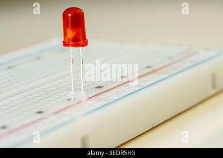 Red LED on breadboard close up, electronic component concept Stock Photo