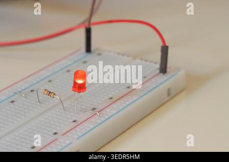 Simple red LED circuit on breadboard with resistor and jumper wires Stock Photo