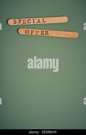 Two wooden sticks with SPECIAL OFFER text on green textured leather background. Vertical view Stock Photo
