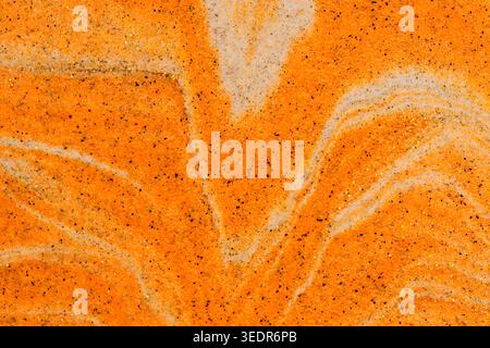 Close up orange sand forming V shaped symmetrical pattern with white layers and gold glitter Stock Photo