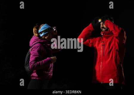 Couple Hikers At Night Wearing Headlamps And Winter Jackets Preparing For Night Trek Stock Photo