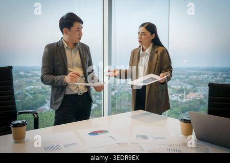 stressed two business colleagues meeting and having a serious argument or disagreement over paperwork in modern office Stock Photo