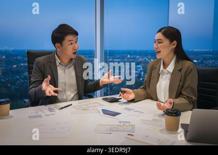 two business colleagues meeting and discussing financial reports and data analysis in modern office at night. Stock Photo
