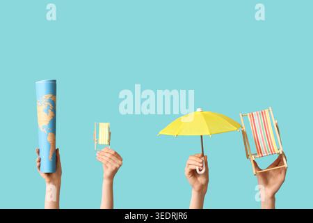 Female hands holding mini deck chairs with umbrella and map on blue background Stock Photo