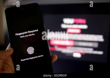 Person holding a smartphone displaying identity verification message for fingerprint authentication, indicating adult content restriction to ensure age verification and digital security Stock Photo