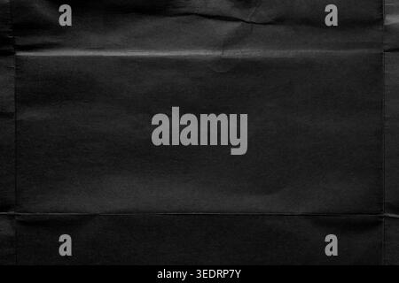 Black paper texture with a fold structure that creates a natural central frame from folds and creases of old unfolded poster. Dark minimalist backgrou Stock Photo