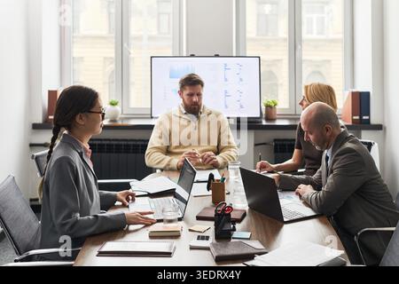 Business team discussing data strategy during office meeting, using laptops and reviewing analytics dashboard. Ideal for corporate planning, teamwork, management communication Stock Photo