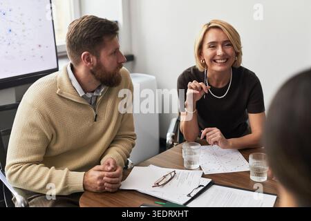 Businesswoman leading meeting with businessman, discussing charts and strategy in office. Ideal for teamwork, leadership, planning, corporate communication Stock Photo