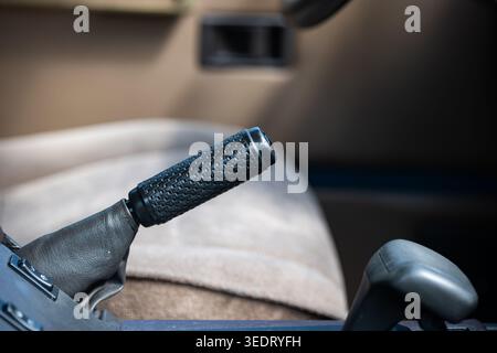 A close up shot of a manual parking brake handle with a patterned grip in a classic car cockpit Stock Photo