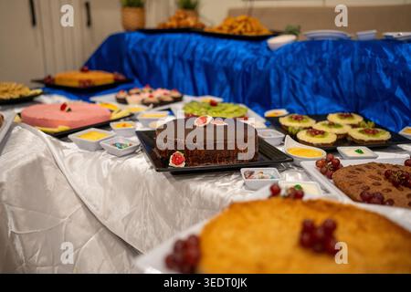 Many colorful cakes and pastry items arranged on a serving table for guests Stock Photo