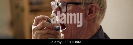 Senior Man Using Inhaler for Asthma Treatment at Home Stock Photo
