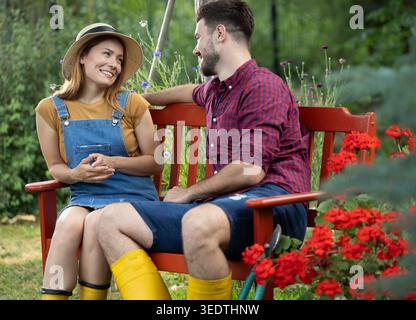 Couple in love sitting on a bench in garden and having a good time while gazing tenderly into each others eyes Stock Photo