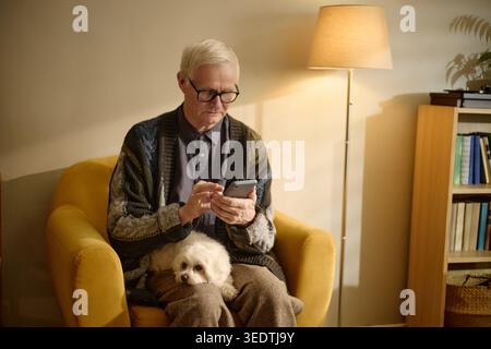 Senior Man Using Smartphone at Home for Digital Communication Stock Photo