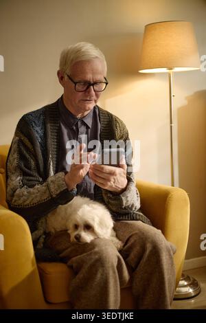 Senior Man Using Smartphone for Remote Communication at Home Stock Photo
