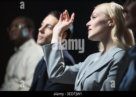 Businesswoman Raising Hand during Corporate Panel Discussion Stock Photo