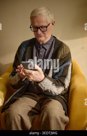 Senior Man Using Smartphone for Online Communication at Home Stock Photo