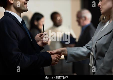 Businessman and Businesswoman Shaking Hands at Networking Event Stock Photo