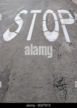 White Stop Sign Painted on Asphalt Road Surface with Top Down Perspective Stock Photo