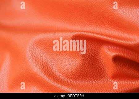 Vibrant orange leather texture showing soft fold and crease details macro photography providing warm comforting feeling with natural material surface Stock Photo