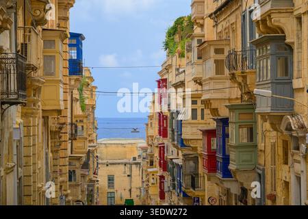 Traditional Maltese balconies with view of coast in Valletta Old Town, Malta. Stock Photo