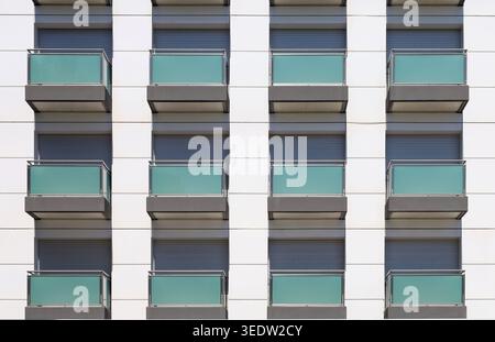 Modern residential building facade with green glass balconies and ventilated facade made of white metal panels.  Background and texture. Stock Photo