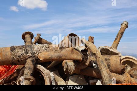 Old rusted and oxide cast iron water pipes, under a blue cloudy sky, removed from a construction site .  Background and texture. Stock Photo