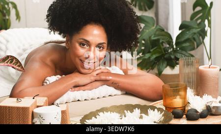 Relaxed Woman Receiving Spa Treatment Surrounded by Candles, Flowers and Aromatherapy Accessories Stock Photo