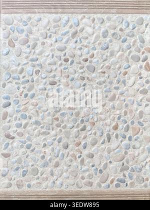 Finishing tiles imitating texture of small sea pebbles in beige and gray tones. Quartz vinyl tile for bathroom or kitchen repairs. Top view Stock Photo